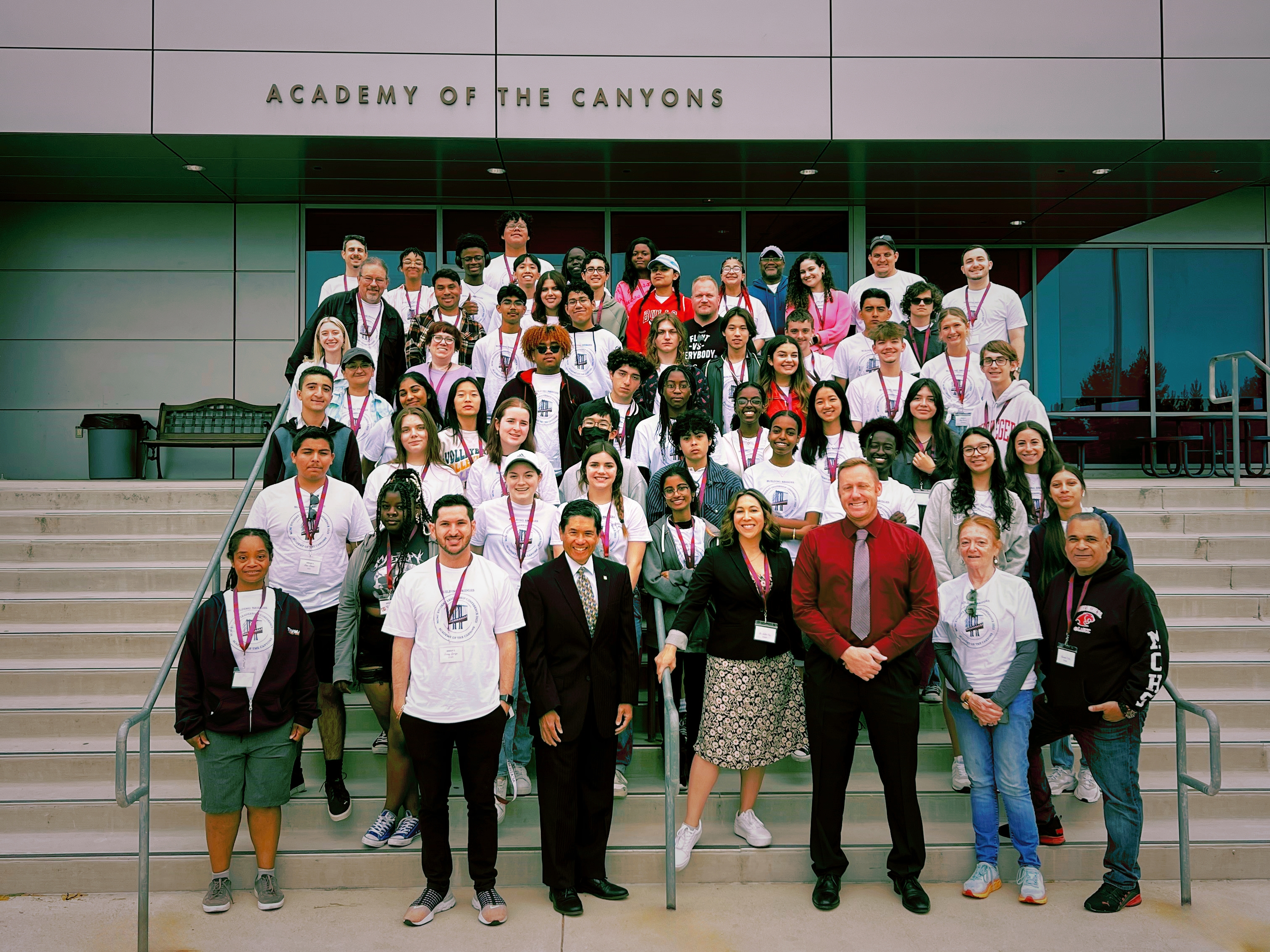 A photo of Ron Yee with students onthe steps of the Academy of the Canyons